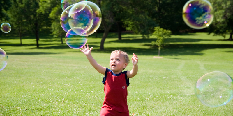 kid playing with bubbles outside during summer