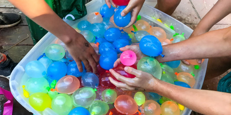 kids having a water balloon fight outside during summer