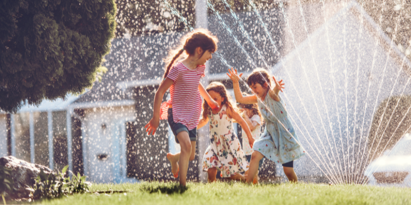 kids playing in sprinkler outside during summer